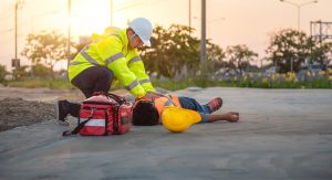 medical worker standing over injured construction worker lying on the ground