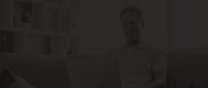 low brightness man looking at a laptop sitting on the couch