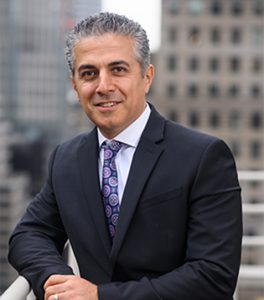 Omrani leaning on railing on new york rooftop