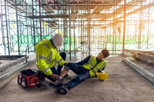construction worker being helped by coworker with ankle injury on site