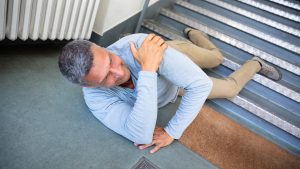 man falling down staircase holding shoulder