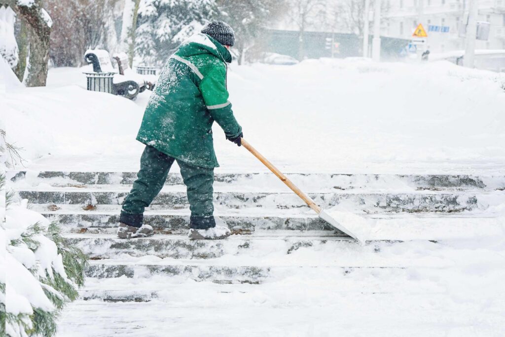Trabajador removiendo nieve durante una tormenta en Nueva York, ilustrando la defensa legal de “tormenta en curso”.