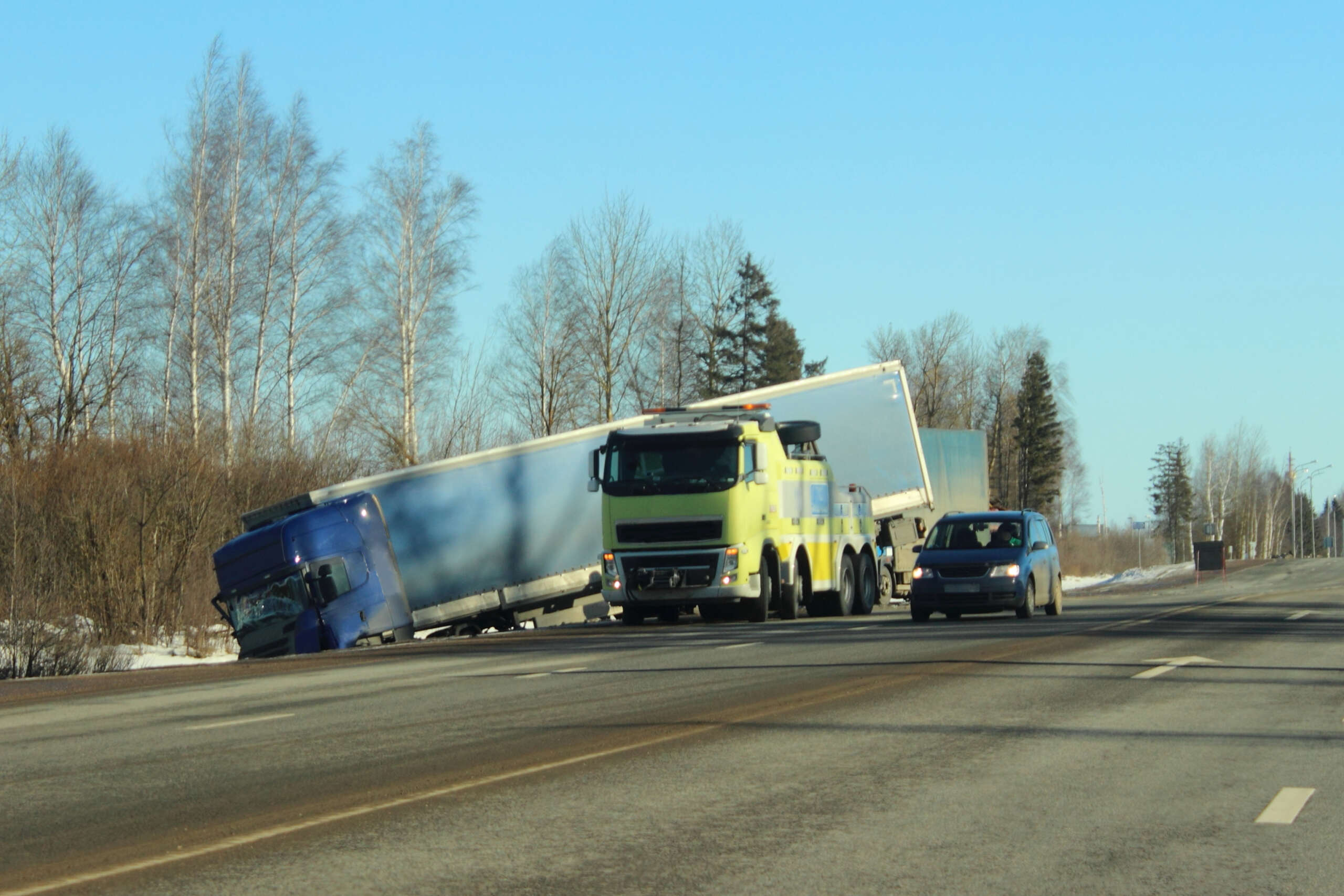 Tow truck recovering a blue semi-truck in a ditch, illustrating suing the broker after a New York truck accident.