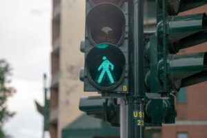 Semáforo peatonal en verde en una calle de Manhattan, representando que cruzar la calle fuera del cruce es legal en NYC