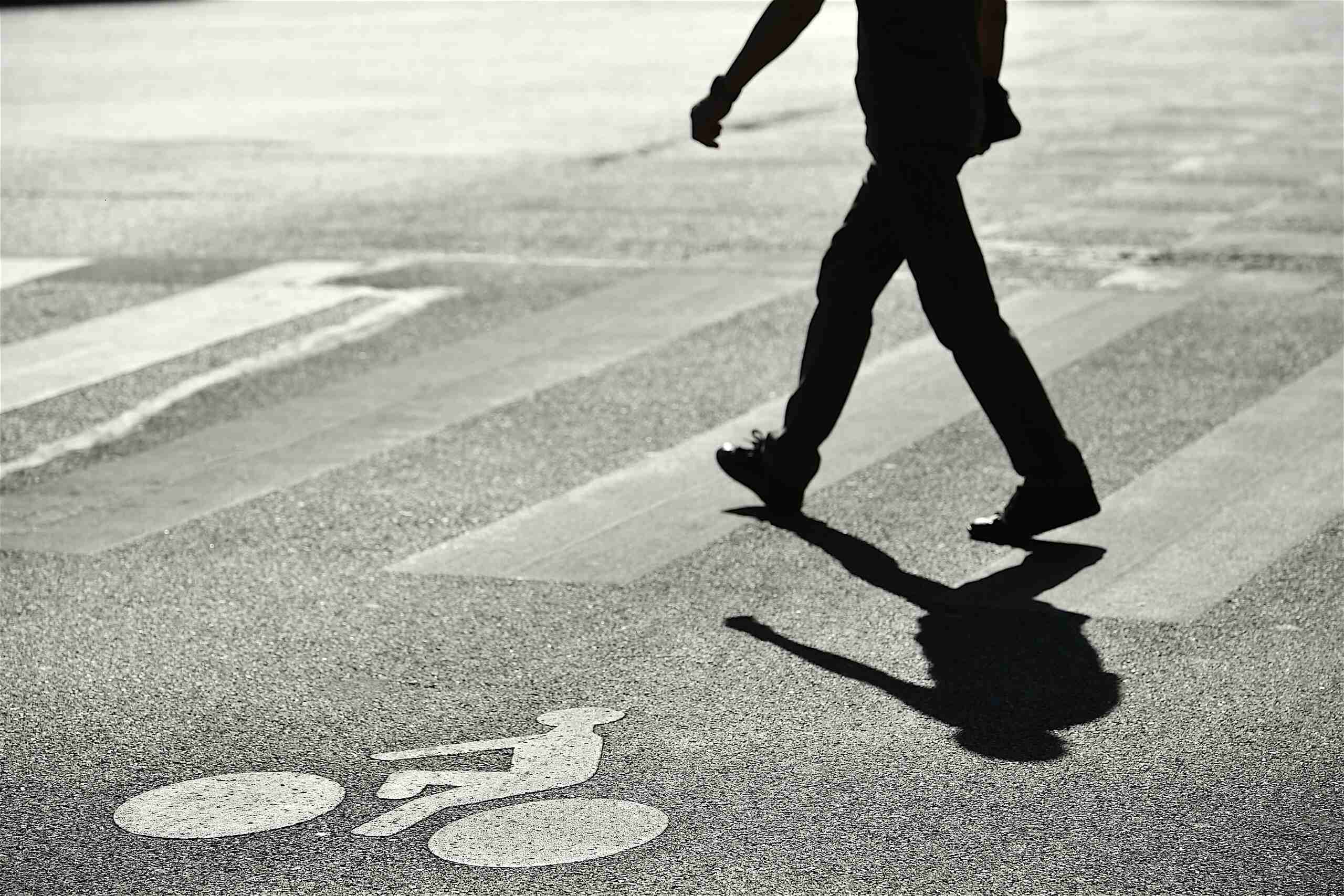 Person walking across a New York crosswalk illustrating a potential pedestrian right of way violation.