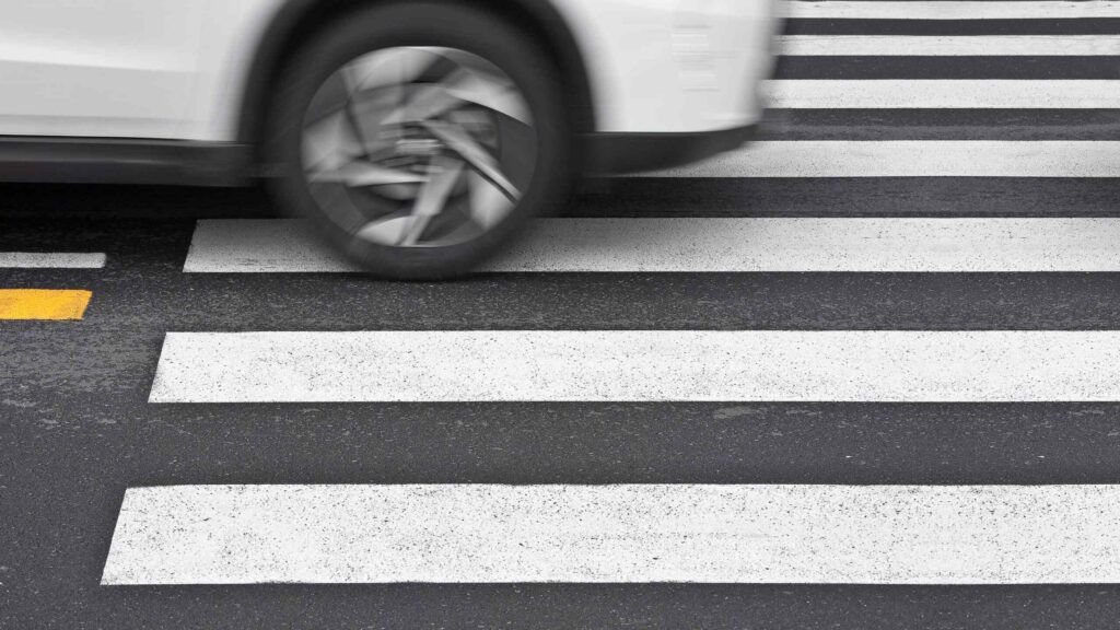 Coche circulando sobre un paso de peatones en una calle de New York, concepto visual de atropello para servicios de abogado de accidentes de peatones.