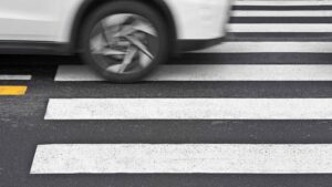 Coche circulando sobre un paso de peatones en una calle de New York, concepto visual de atropello para servicios de abogado de accidentes de peatones.