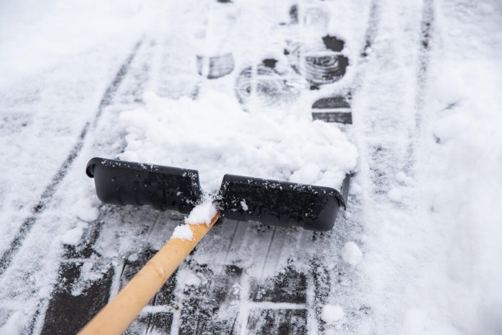 Snow being cleared from a New York sidewalk during active snowfall, illustrating the “storm in progress” defense.