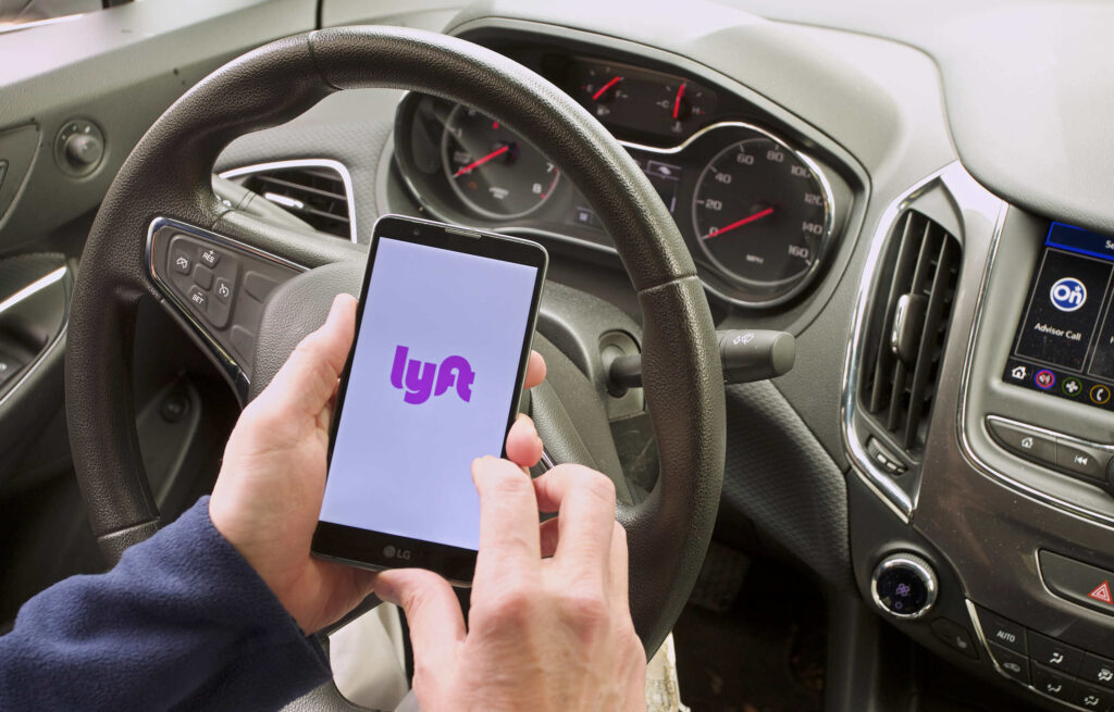 Conductor usando la aplicación de Lyft en Nueva York, representando la incertidumbre sobre qué seguro aplica tras un choque.