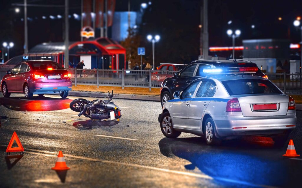 Escena de un accidente de motocicleta en Nueva York por la noche con presencia policial, destacando la necesidad de representación legal inmediata.