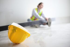 A yellow hard hat on a New York construction site floor near an injured worker, representing evidence used to prove negligence through site safety logs.