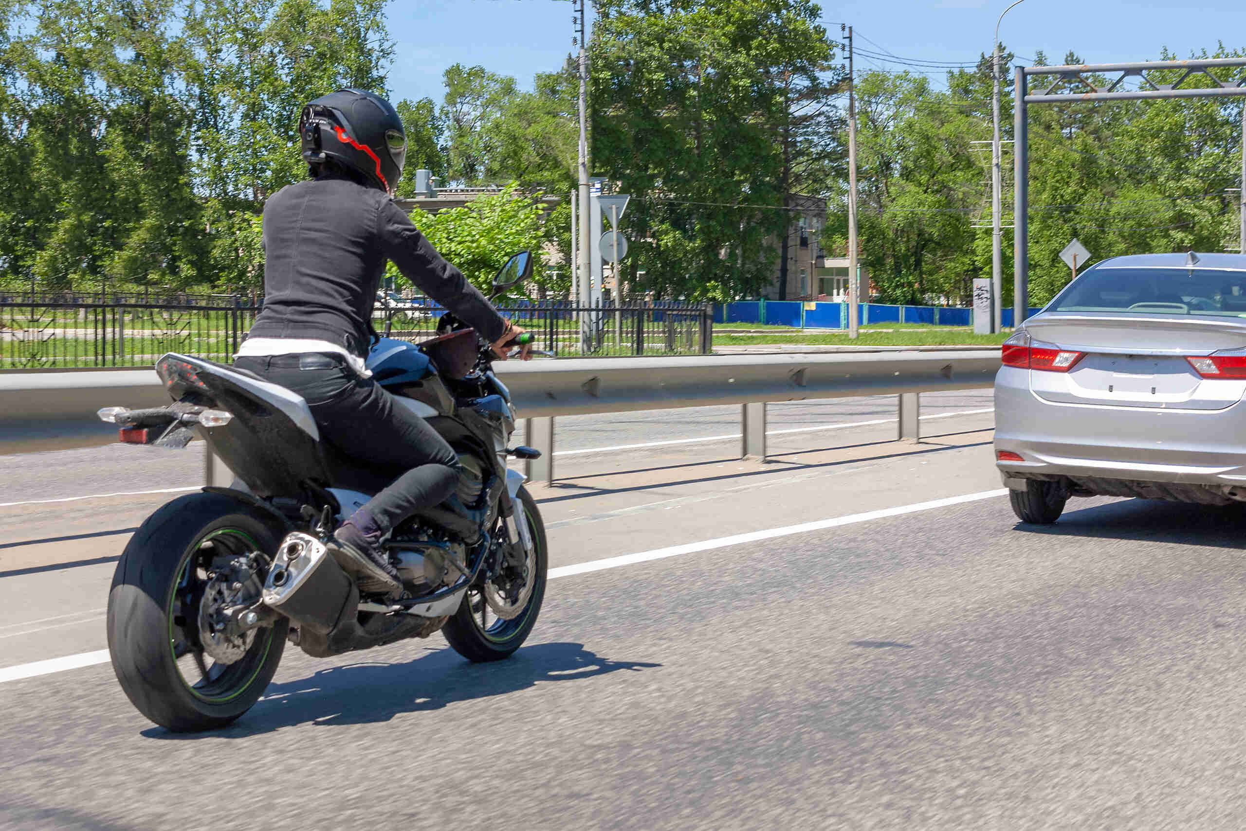A motorcycle rider in NYC navigating close to a passenger vehicle, representing a lane filtering scenario common in injury lawsuits.