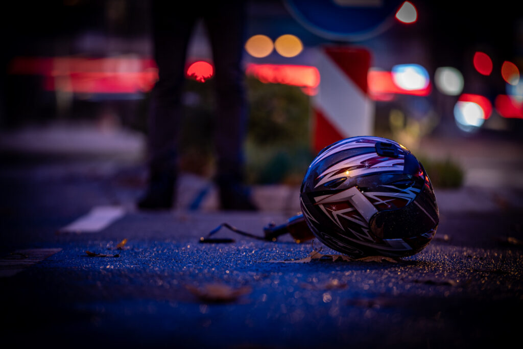 A motorcycle helmet on a dark New York street after a life-altering crash, illustrating the lack of physical protection for riders.