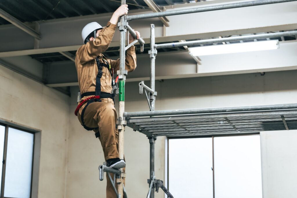 Construction worker climbing a scaffold on a New York site where third-party contractors share responsibility for safety equipment maintenance.