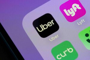 A close-up view of a smartphone screen showing the Uber, Lyft, and Curb mobile app icons.
