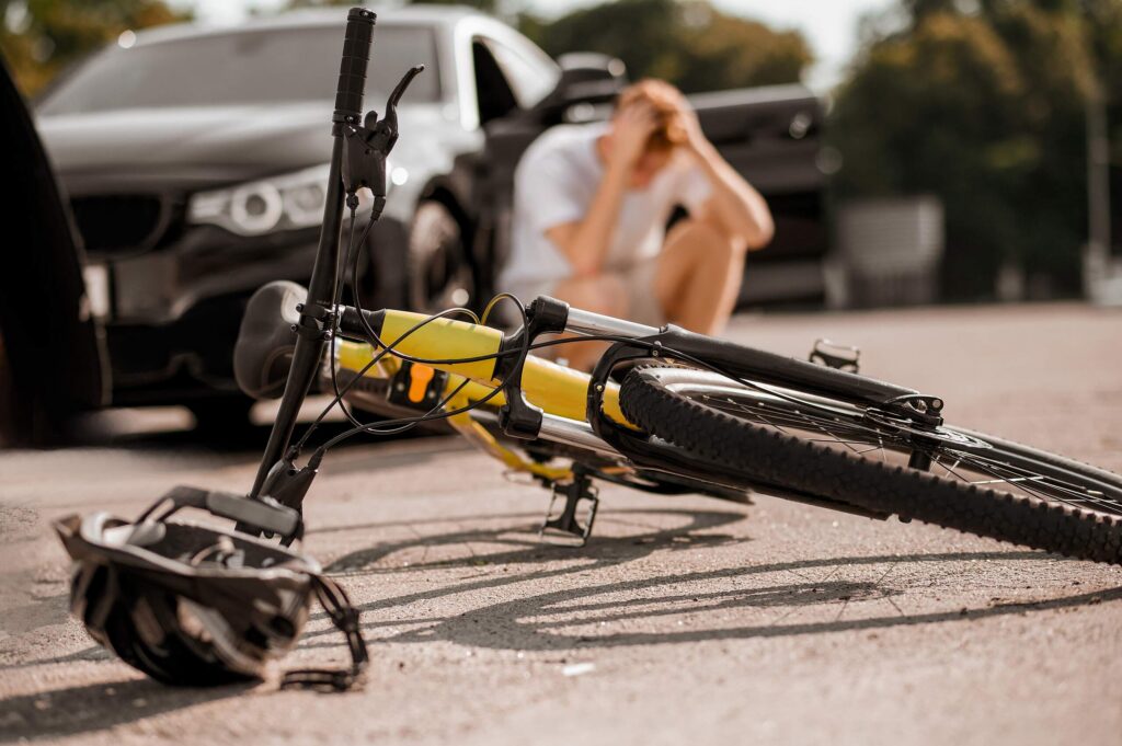 Cyclist injured in a New York bicycle accident beside damaged vehicle after roadway collision