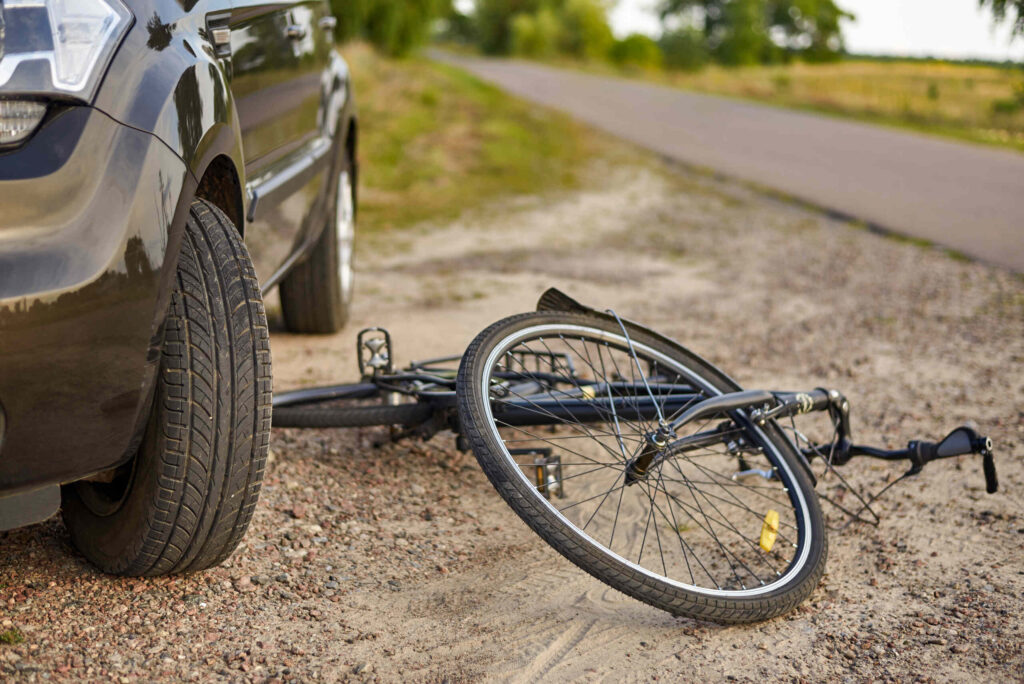Damaged bicycle beside parked vehicle after a New York bicycle dooring accident involving an opened car door