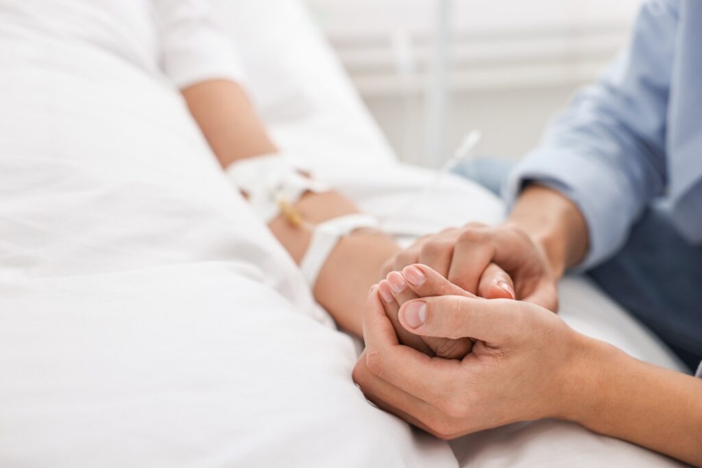 Una persona sosteniendo la mano de un familiar hospitalizado representa los reclamos sobre cómo funciona la acción de sobrevivencia.