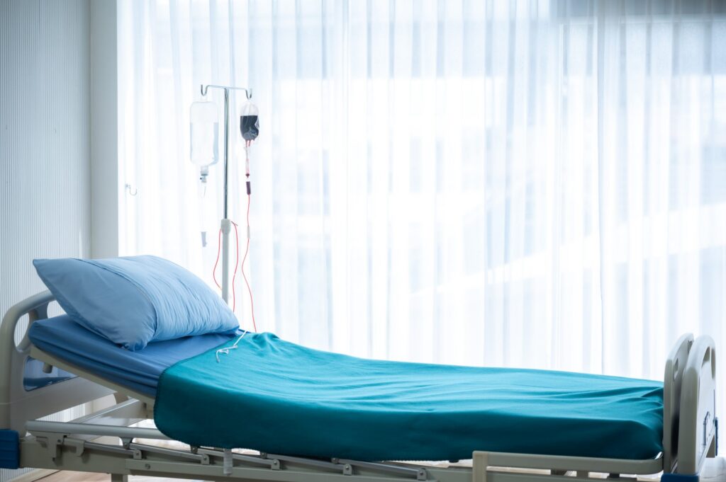 An empty hospital bed with an IV drip illustrates pre death losses in a Wrongful Death vs. Survival Action in New York.