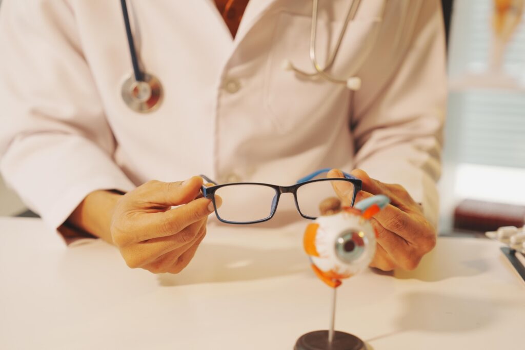 An eye doctor holding eyeglasses near a model eye illustrating surgical errors in NYC hospitals.