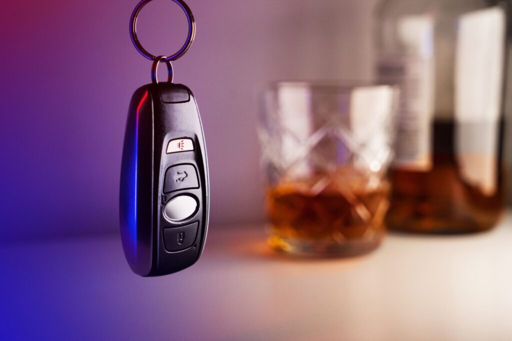 Llave de vehículo junto a un vaso de alcohol ilustrando los accidentes de DWI felony vs misdemeanor en NY cargos penales.