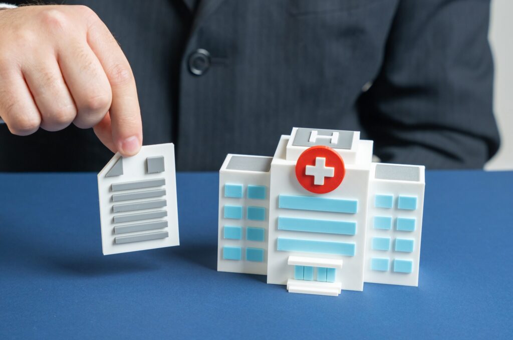 Person placing a medical report document next to a toy hospital to illustrate undocumented workers rights and construction accidents in NY.